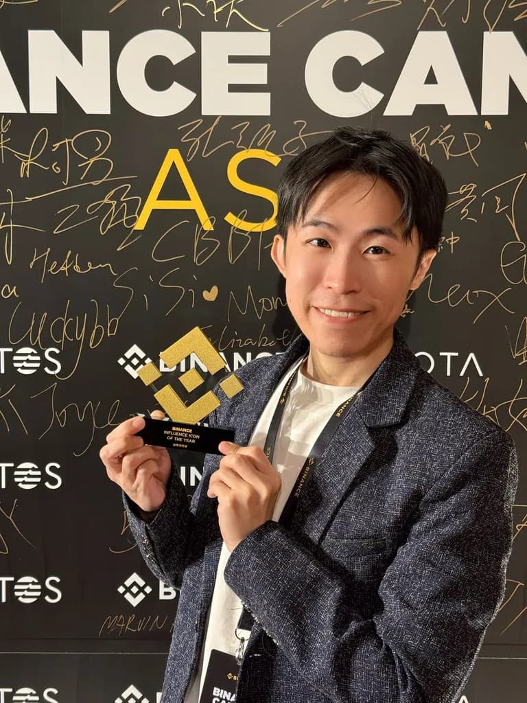 氣球柯男手持幣安年度影響力達人獎獎座，站在 Binance Campus Asia 簽名牆前