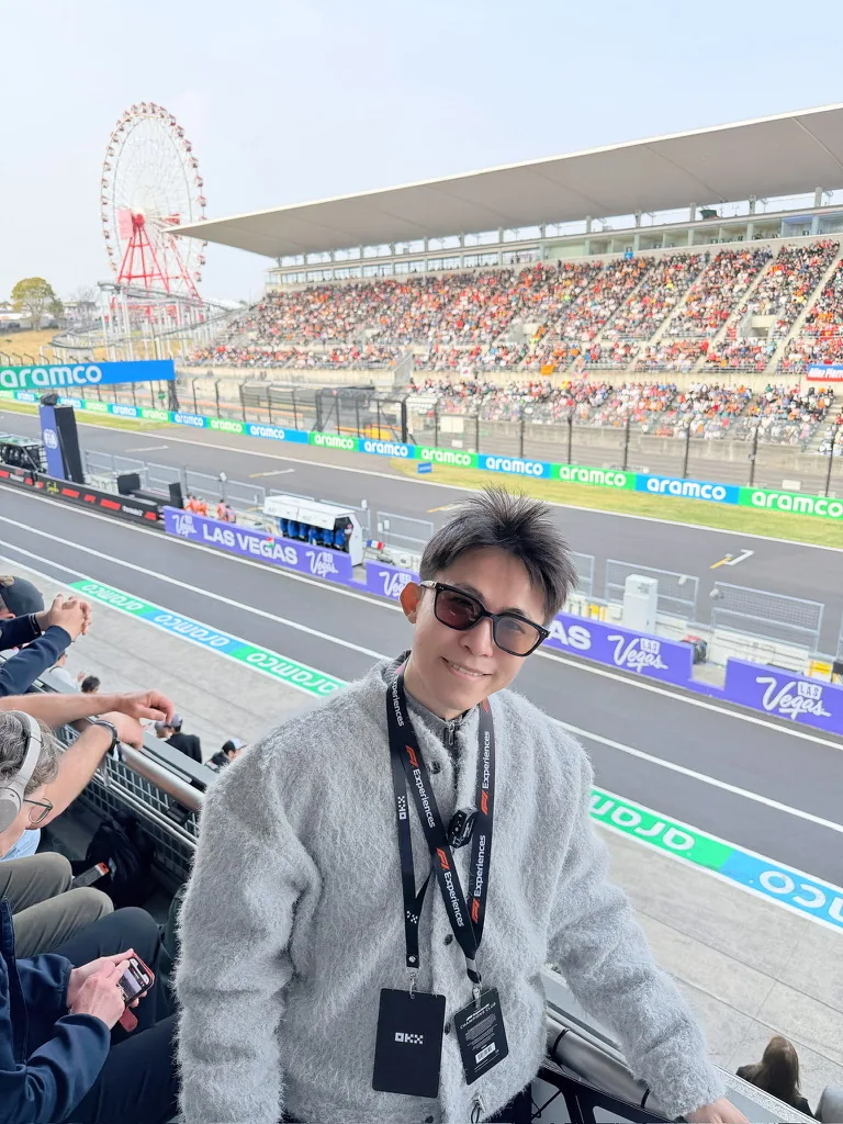 氣球柯男在日本鈴鹿賽道 F1 VIP 區,背景為主看台、Aramco 廣告與摩天輪