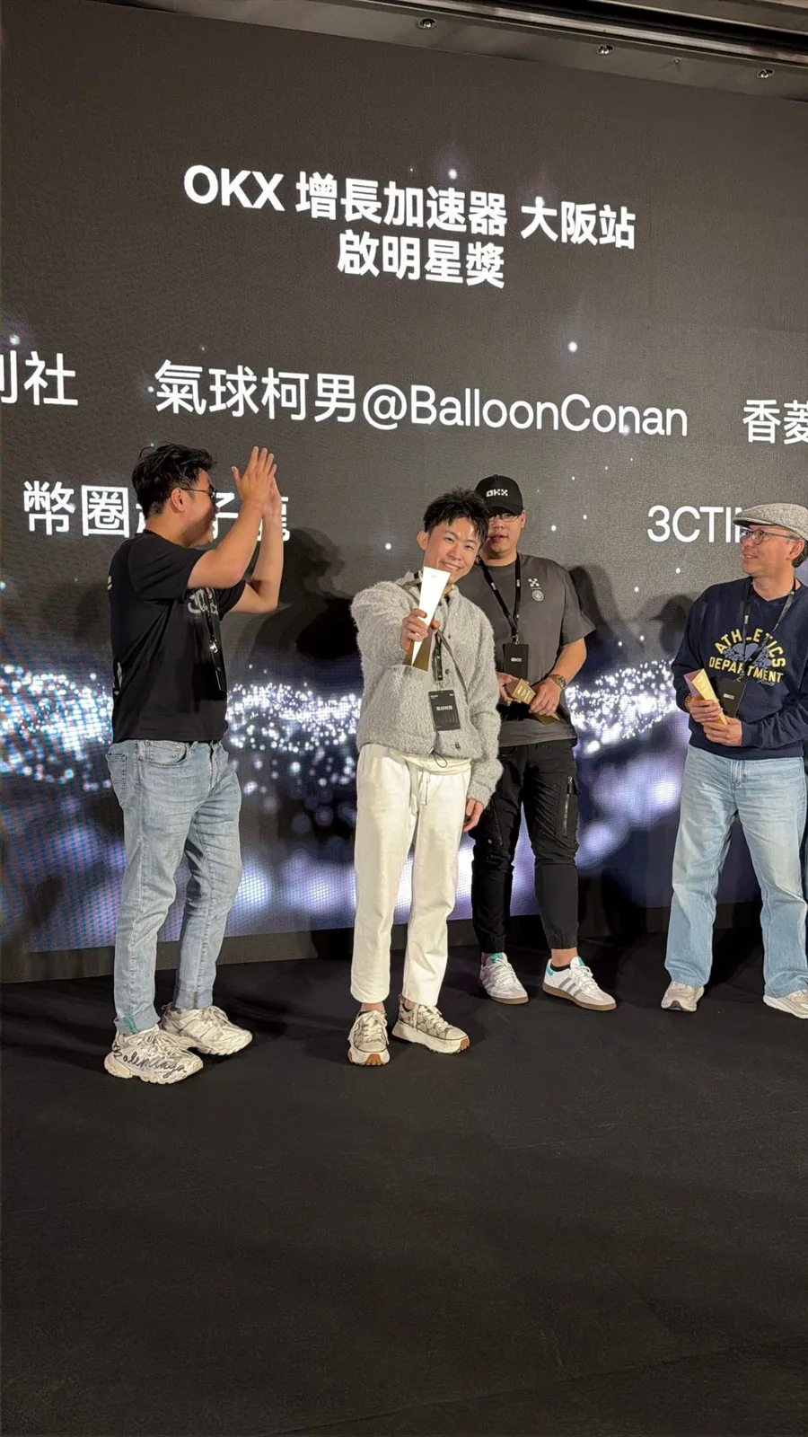 OKX 增長加速器大阪站頒獎台,大螢幕顯示啟明星獎與「氣球柯男@BalloonConan」,柯男手持獎座